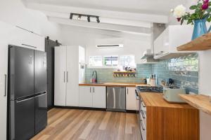 a kitchen with white cabinets and a black refrigerator at Bawley Point Beach House - renovated beach escape in Bawley Point