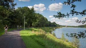 Zwei Personen fahren mit Fahrrädern auf einem Weg neben einem Fluss in der Unterkunft Komfortable Ferienwohnung mit Seeblick in Bad Arolsen