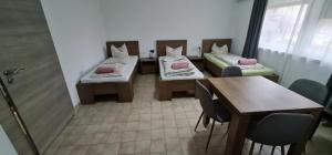 a room with two beds and a table and chairs at Vándor Szálló in Kecskemét +1 photo
