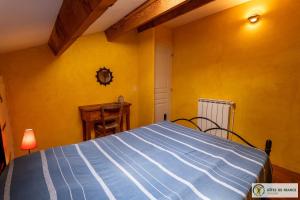 - une chambre avec un lit bleu dans un mur jaune dans l'établissement Le Gîte de Saint Izaire, à Broquiès