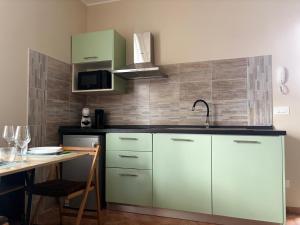 a kitchen with green cabinets and a table and a sink at Elegante bilocale a due passi dal centro in Saluggia