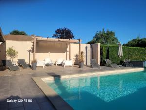 una piscina con un grupo de sillas y una sombrilla en Gîte Yanou, en Sault-de-Navailles