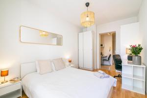 ein weißes Schlafzimmer mit einem weißen Bett und einem Schreibtisch in der Unterkunft Simplon Residence - Central and Self Check In in Lausanne