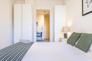 ein Schlafzimmer mit einem großen weißen Bett und grünen Kissen in der Unterkunft Simplon Residence - Central and Self Check In in Lausanne