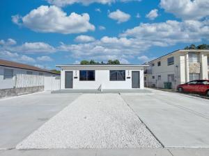 a white house with a car parked in a driveway at Lux Miami Escape - Near Brickell- Free Parking in Miami