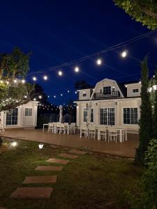 a white house with white tables and chairs at night at Samonrada Khao Yai Homestay in Pak Chong