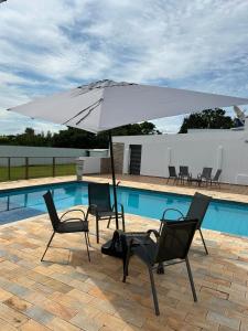 Una sombrilla y sillas junto a una piscina. en Pousada Vale Canastra, en São João Batista do Glória