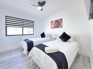 two beds in a white room with a ceiling fan at Lux Miami Escape - Near Brickell- Free Parking in Miami
