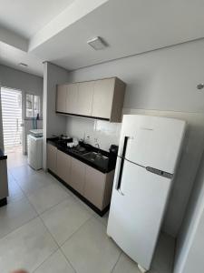 a kitchen with a white refrigerator in a room at Apartamento com jardim e ar condicionado na sala e quartos na Av Blumenau in Sorriso