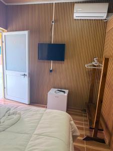 une chambre avec un lit et une télévision sur un mur dans l'établissement Residencial Bom Desc & Conforto, à Santo António