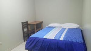 una camera da letto con un letto blu e bianco e un tavolo di Hospedaje El Encanto a Huancayo