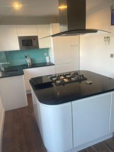 Una cocina con gabinetes blancos y una encimera negra. en Cassandra Homes, en Nevendon