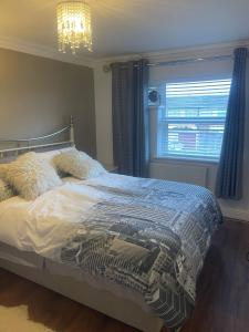 Un dormitorio con una cama y una ventana y una lámpara de araña. en Cassandra Homes, en Nevendon