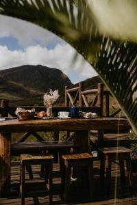 a wooden table with chairs and a table with mountains in the background at Vale do Elefante - Casa com Jacuzzi e Cachoeira in Santana do Riacho +52 photos