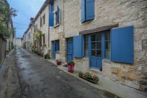 Une allée avec volets bleus dans un bâtiment en pierre dans l'établissement La Maison de Julie - Proche Sites Historique, à Septfonds