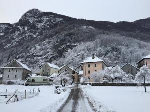 Un pueblo cubierto de nieve con casas y una montaña. en Rustico Di Vacanza Nel Nucleo Di Moghegno, en Moghegno