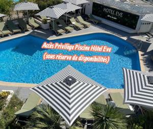 an overhead view of a swimming pool with umbrellas and chairs at Villa 26, La Palmeraie au village naturiste in Cap d'Agde