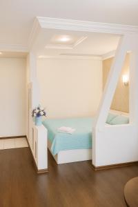 a white bedroom with a bed and a staircase at Білі апартаменти на Кельнському бульварі in Dnipro