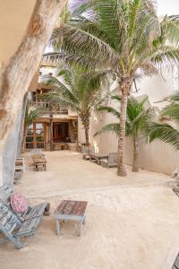 a courtyard with palm trees and lounge chairs in a building at La Posada del Sol Boutique Hotel Tulum in Tulum