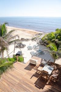 a wooden deck with chairs and tables on a beach at La Posada del Sol Boutique Hotel Tulum in Tulum