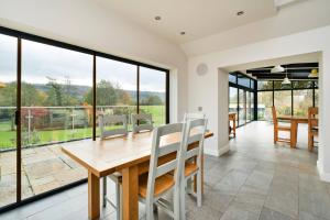 Un comedor con mesa y sillas y grandes ventanales. en Yonder, en Harley