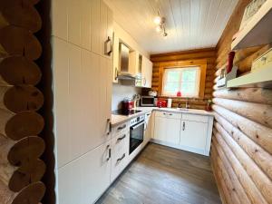 - une cuisine avec des placards blancs et un mur en bois dans l'établissement villa kunterBUNT, à Grödersby