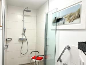 La salle de bains est pourvue d'une douche et d'un tabouret rouge. dans l'établissement villa kunterBUNT, à Grödersby 26 autres photos