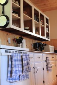 La cuisine est équipée de placards blancs et d'un four avec plaques de cuisson blanches. dans l'établissement The Nook - Sherbrooke Cottages, à Summerside
