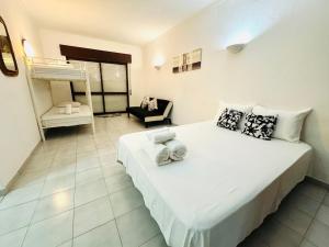 a bedroom with a large white bed and a chair at Apartamento gourmet com quintal in Albufeira