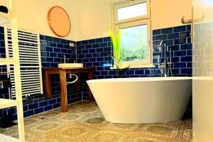 - une salle de bains carrelée de bleu pourvue d'une baignoire et d'une fenêtre dans l'établissement Romantikferienhaus am Schlösschen - Sauna, Kamin & Seenlandschaft nahe Berlin, à Marienwerder 48 autres photos