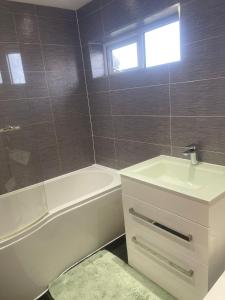 y baño con lavabo blanco, bañera y lavamanos. en Cassandra Homes, en Nevendon