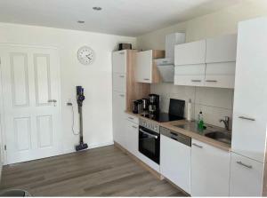 a kitchen with white cabinets and a clock on the wall at Seaside-Amrum-8 in Norddorf
