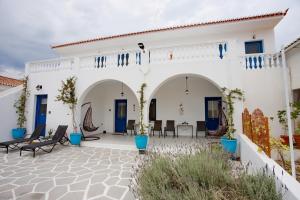 un bâtiment blanc avec des portes et des chaises bleues dans l'établissement Villa Jenny Stylianou, à Spetses