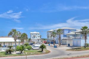 a street with houses and palm trees and a road at Ocean Waves in Port Aransas