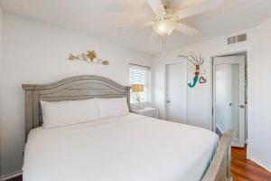 a bedroom with a white bed and a ceiling fan at Beach Club 323 in Padre Island +30 photos