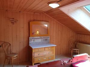 Una habitación con una cómoda y dos sillas y un espejo. en Barba Peder Biobergün, en Bergün