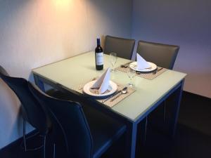 a table with chairs and a bottle of wine and glasses at Gemütliche Ferienwohnung Im Disentiserhof in Disentis