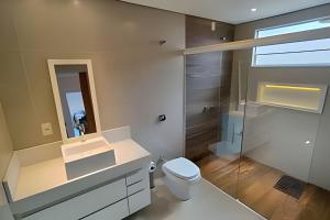 une salle de bain avec toilettes, lavabo et miroir dans l'établissement Casa familiar 2 qts, próx. ao Santuário Nacional, à Aparecida 27 autres photos