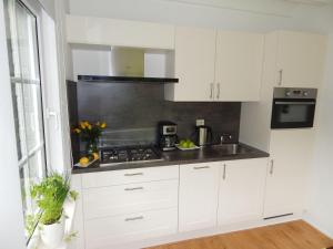 une cuisine avec des armoires blanches et un four à plaques de cuisson dans l'établissement Traumhaftes-freistehendes-Ferienhaus-an-der-See-Strand-Yachthafen-W-Lan, à Bruinisse