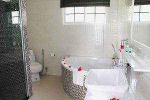 a bathroom with a tub and a toilet and a sink at H & M Bayview Apartment Seychelles in Beau Vallon