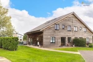 a large wooden barn on a green lawn at Waters Edge 16, Heron Lodge in South Cerney