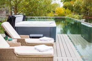 a hot tub sitting on a deck next to the water at Waters Edge 16, Heron Lodge in South Cerney
