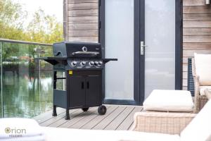 a barbecue grill on a deck with a patio at Waters Edge 16, Heron Lodge in South Cerney