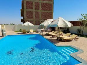 a swimming pool with lounge chairs and umbrellas at Saray El Omda - Wellness & Retreat Village in Luxor
