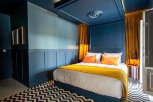 a bedroom with blue walls and a bed with orange pillows at &Tales Hotel - Óbidos in Óbidos +34 photos