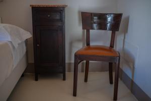 a wooden chair sitting next to a bed and a dresser at La Carrera in Bernalda