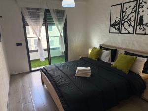 a bedroom with a large black bed with green pillows at Studio Stadium morocco for family in Mohammedia +43 photos