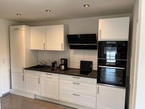 a kitchen with white cabinets and black appliances at Seaside-Amrum-11 in Norddorf