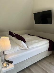 a bed with white sheets and pillows and a television at Seaside-Amrum-11 in Norddorf