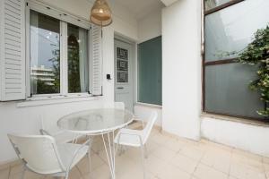 eine Terrasse mit einem weißen Tisch und Stühlen und einem Fenster in der Unterkunft Bright & Cozy House near Beach in Athen